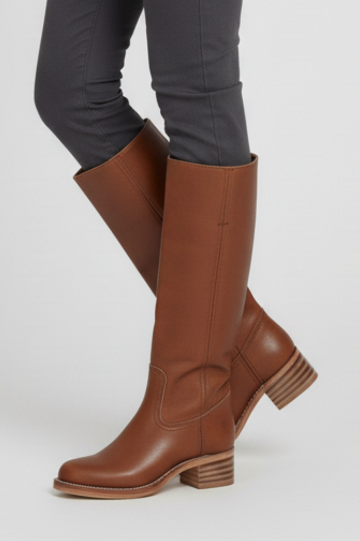 Brown knee-high boots worn with gray pants on a white background