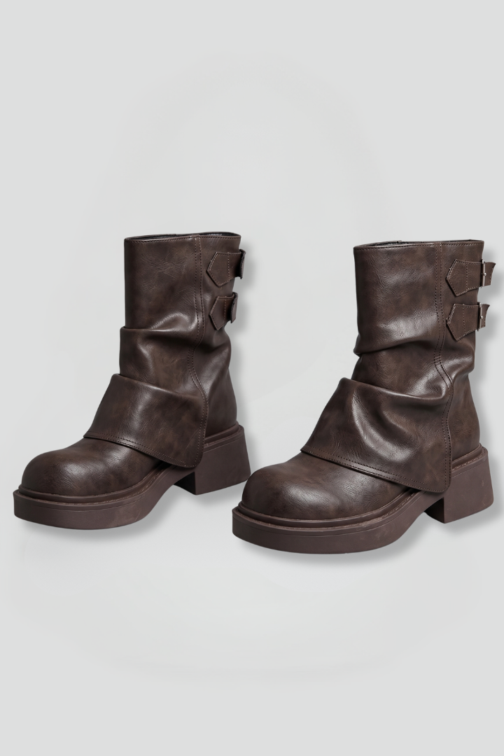 Pair of brown leather boots with buckles on a light gray background