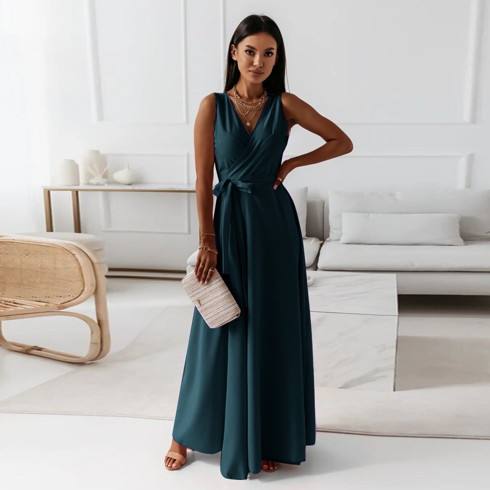 Woman in a teal dress holding a clutch in a modern living room.