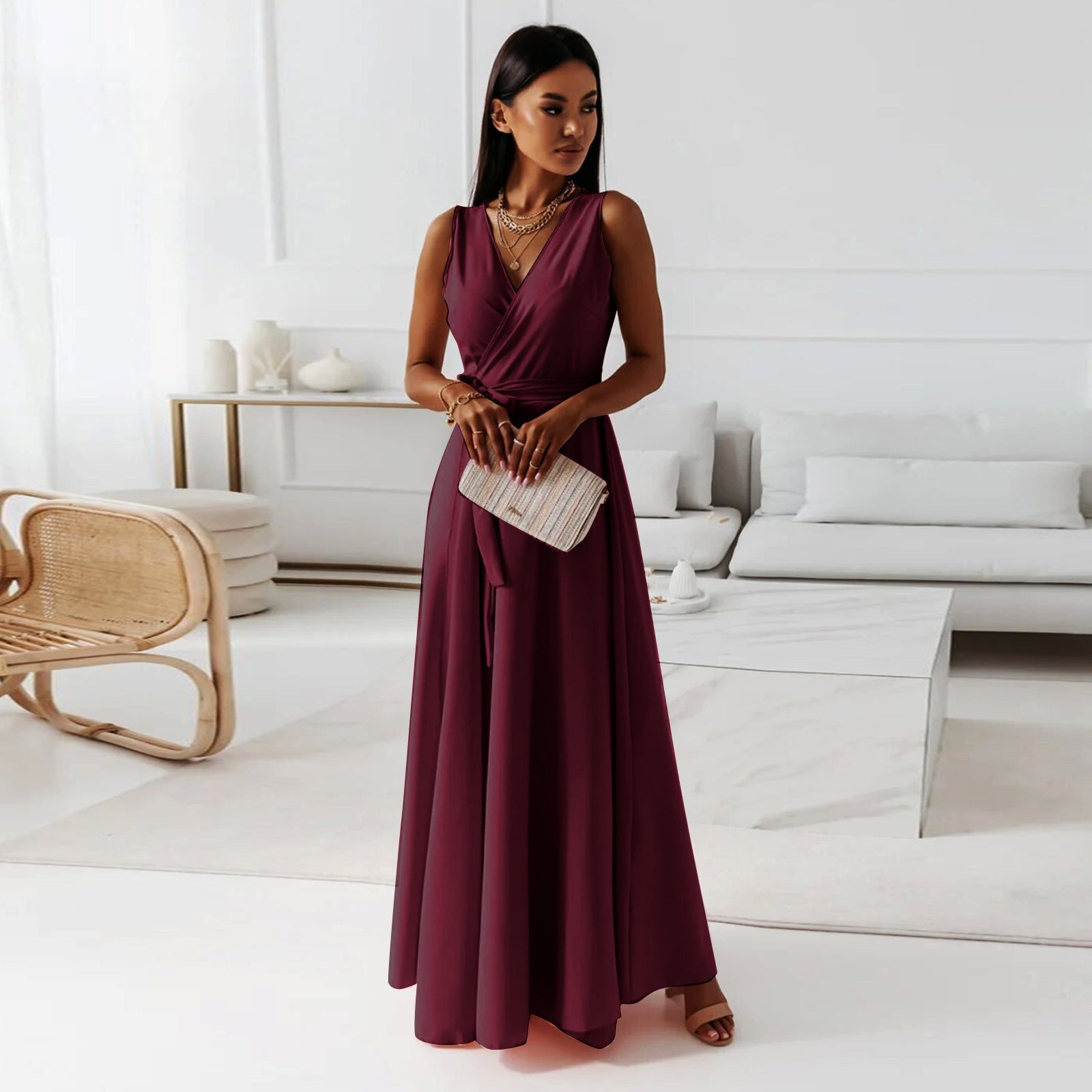 Woman in a burgundy dress holding a clutch in a modern living room.
