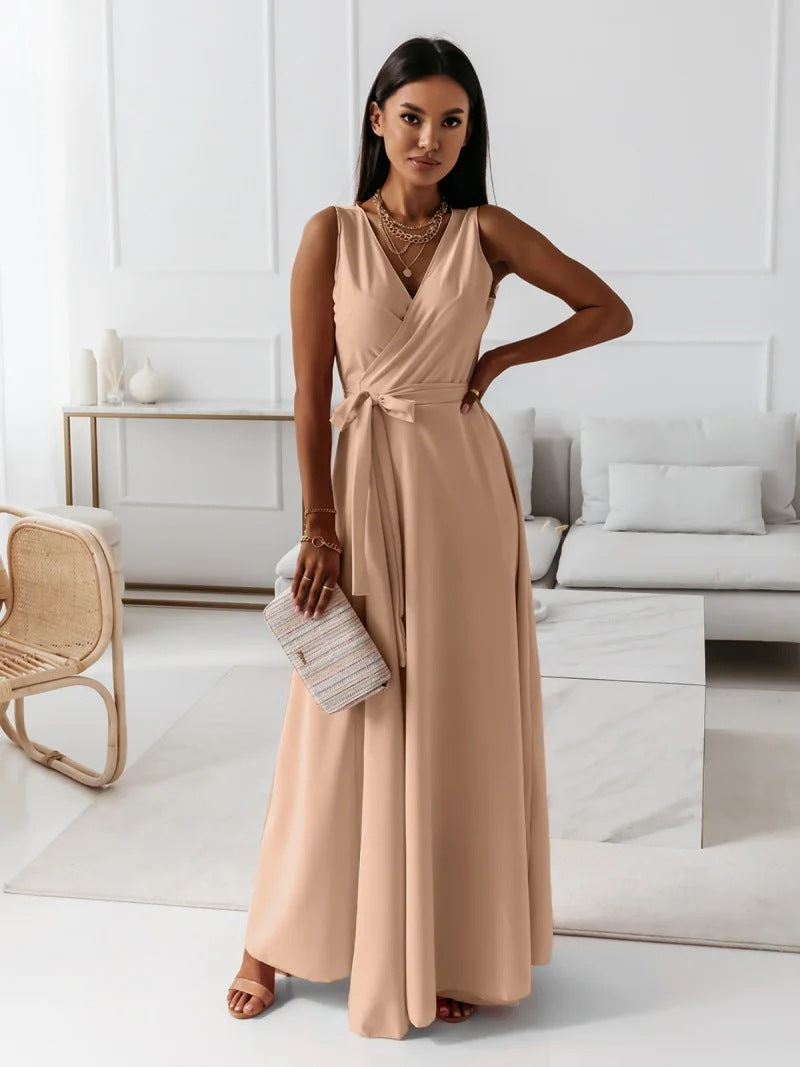 Woman in a long beige dress holding a clutch in a modern living room.