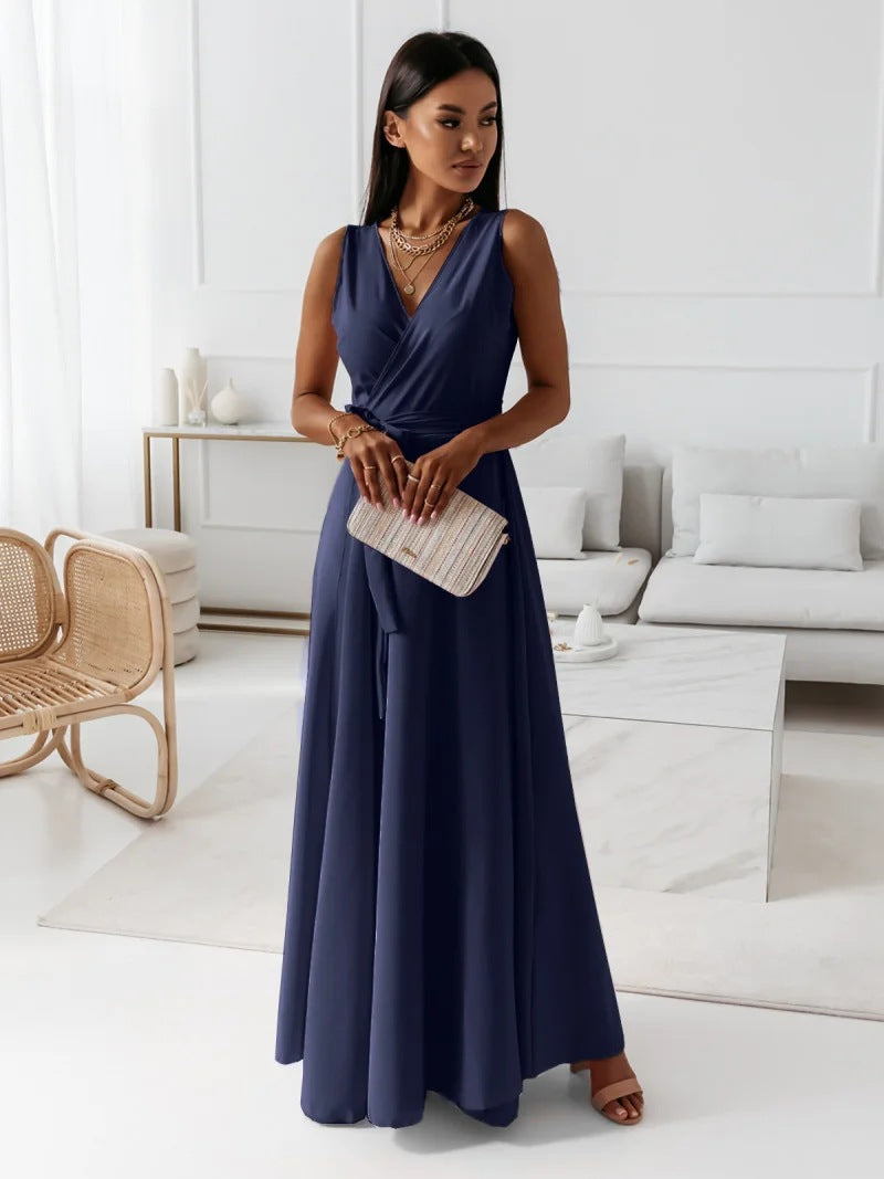 Woman in a navy blue dress holding a beige clutch in a modern living room.