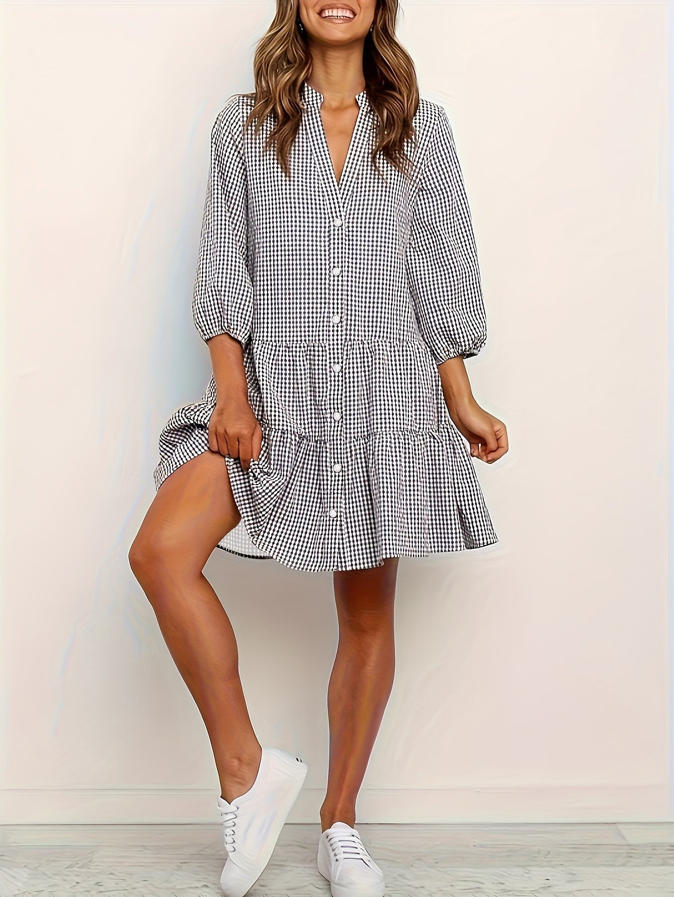 Woman wearing a checkered dress with white sneakers on a plain background