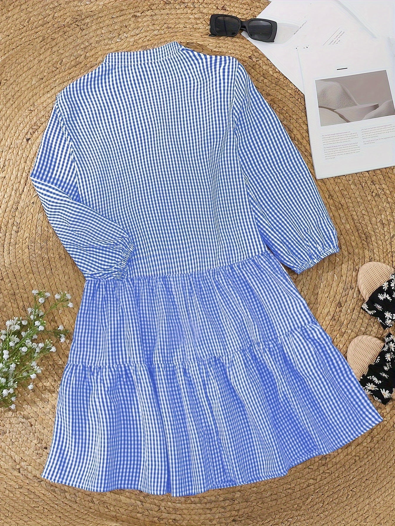 Blue checkered dress on a textured surface with a bow and magazine in the background