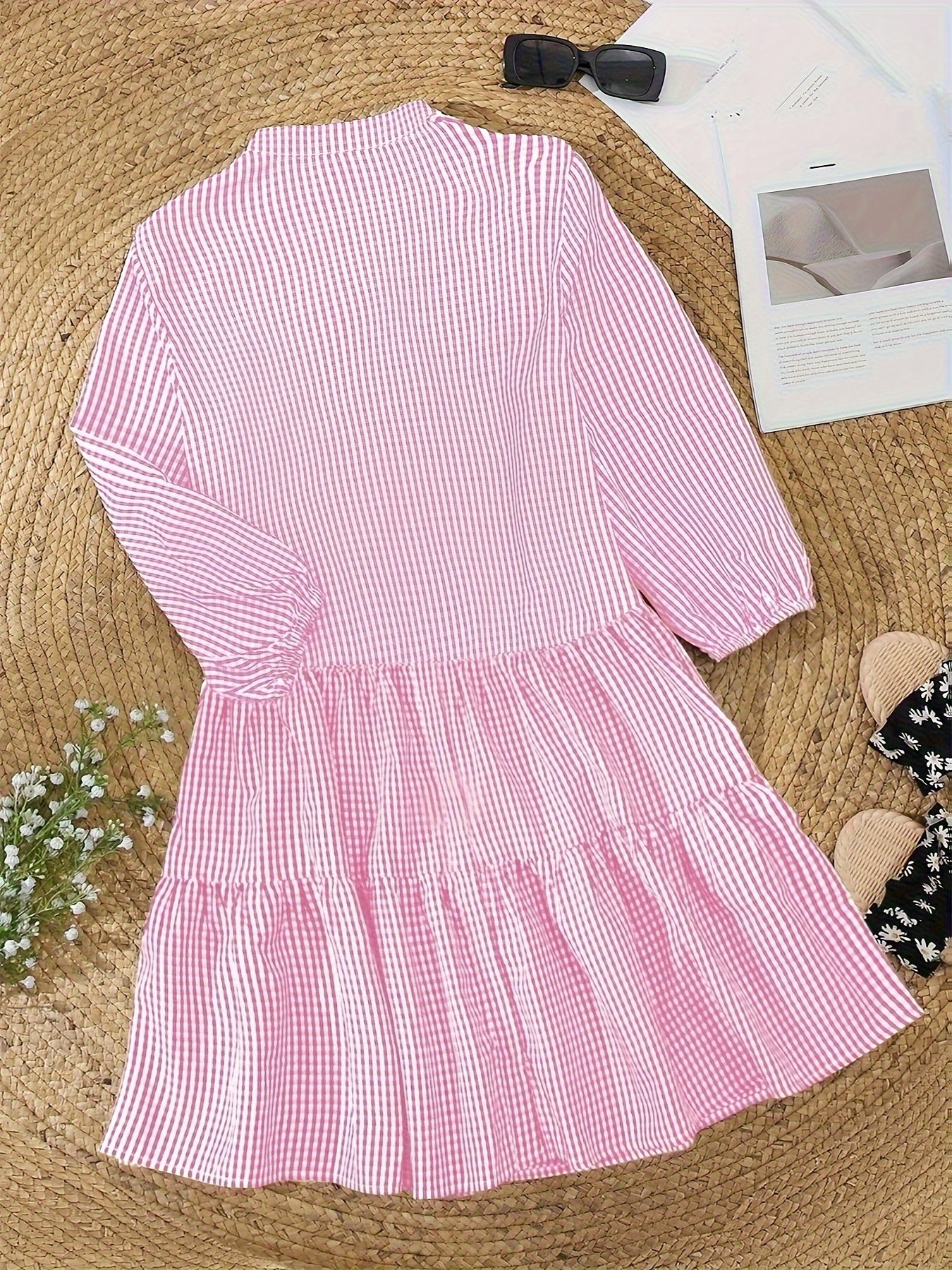 Pink and white striped dress on a textured surface with a bow and paper in the background.