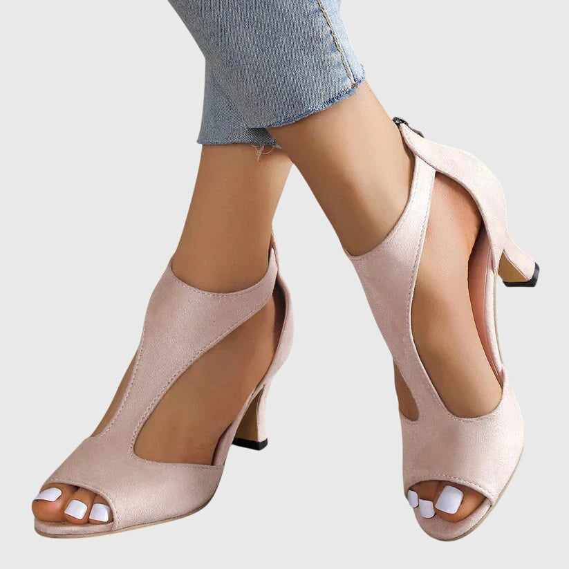 Beige open-toe high-heeled shoes worn with light blue jeans on a white background