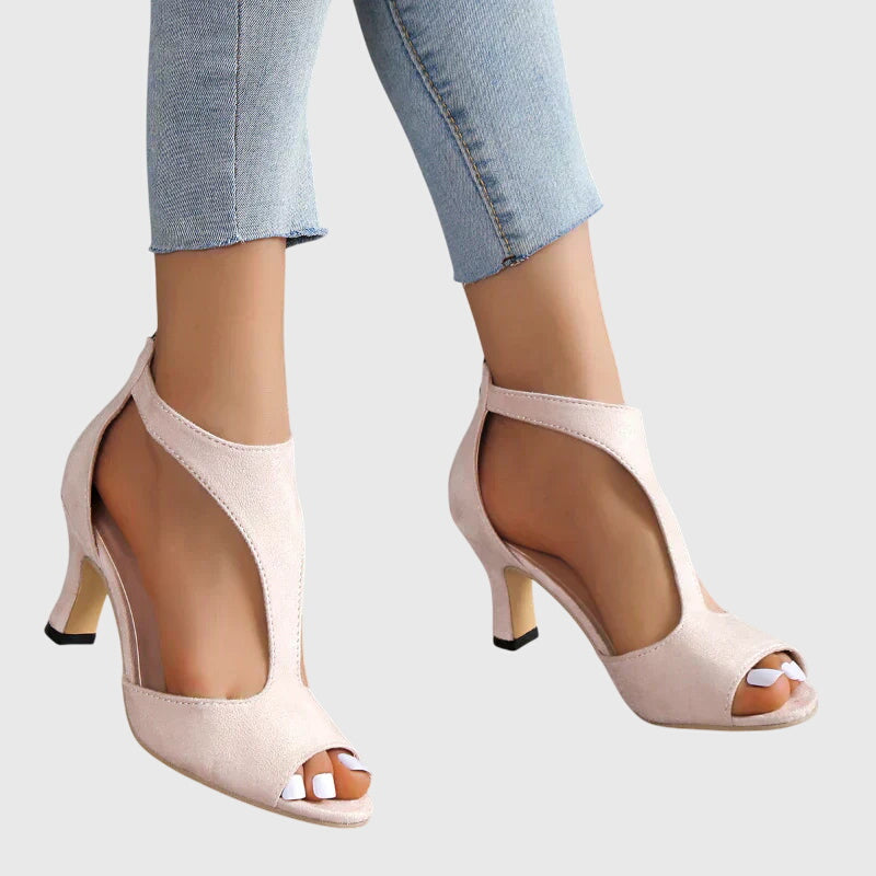 Beige high-heeled shoes worn with light blue jeans on a white background