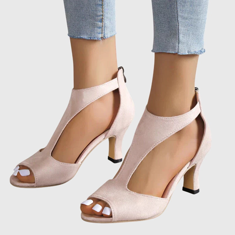 Beige high-heeled shoes worn with light blue jeans on a white background