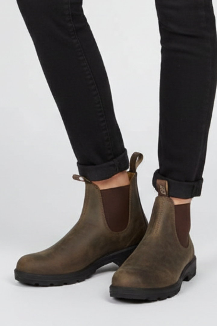 Brown leather Chelsea boots worn with black jeans on a white background