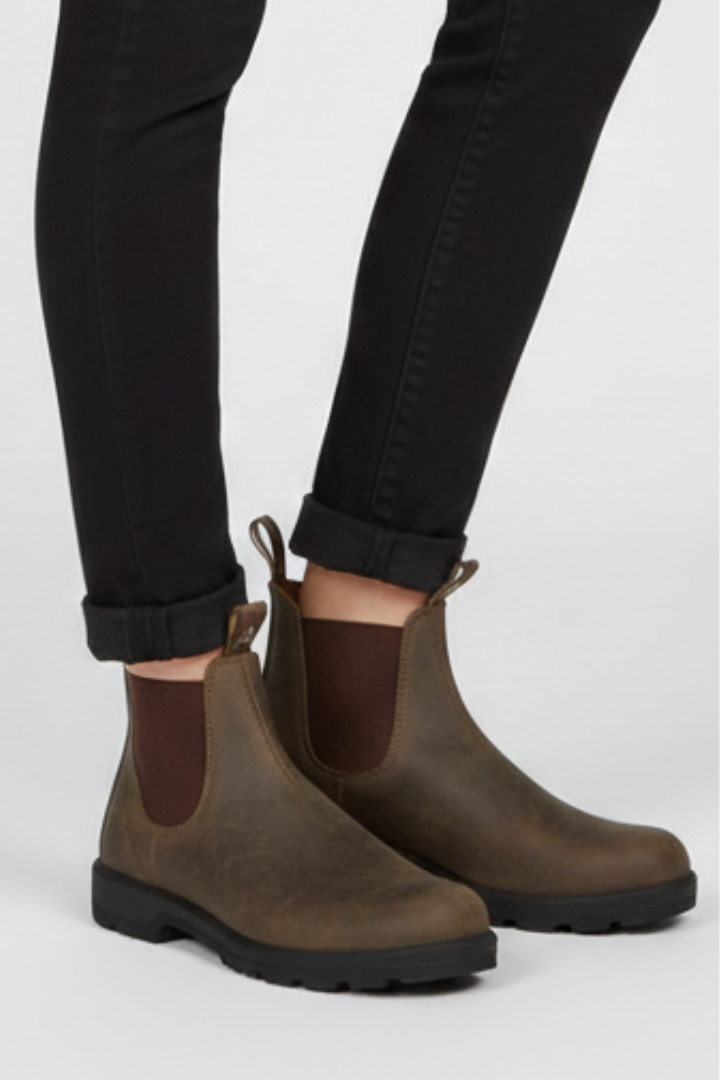Brown Chelsea boots worn with black pants on a white background