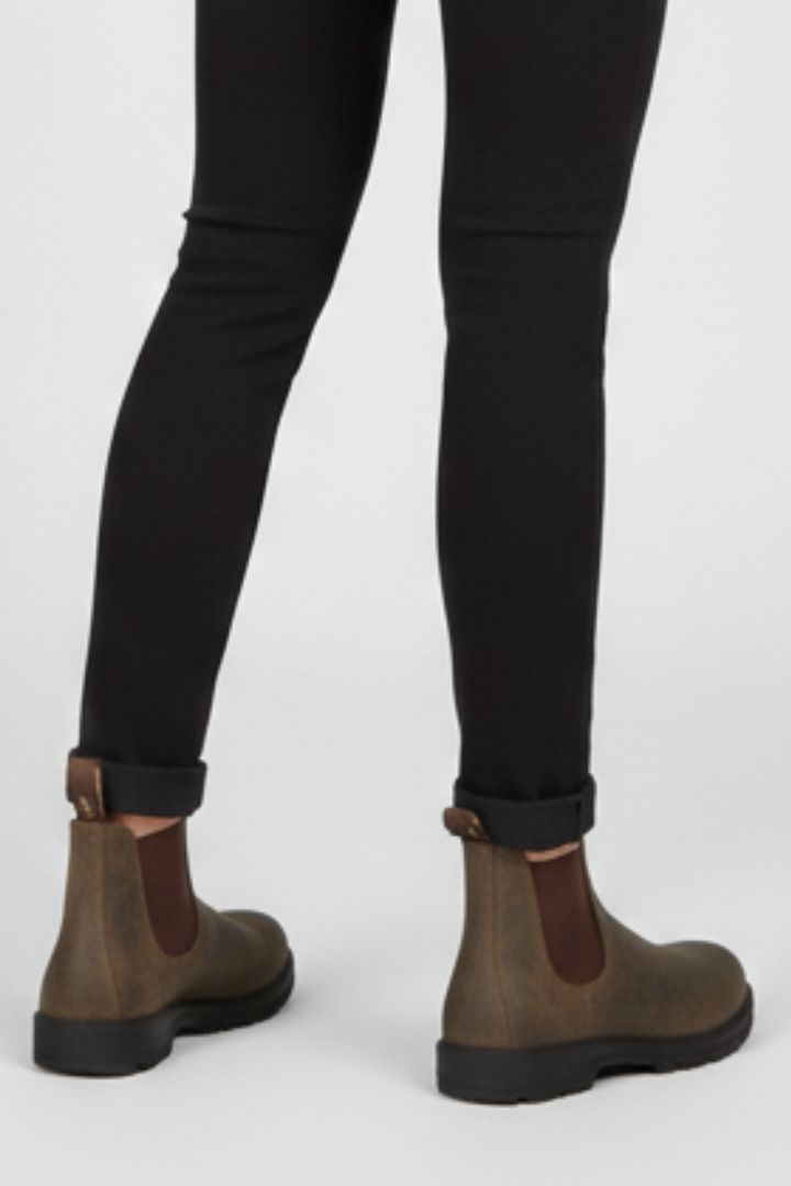 Brown Chelsea boots worn with black pants on a white background