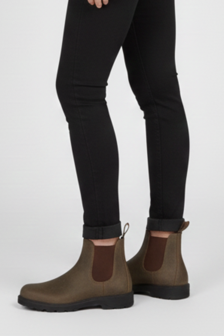 Brown Chelsea boots worn with black pants on a white background