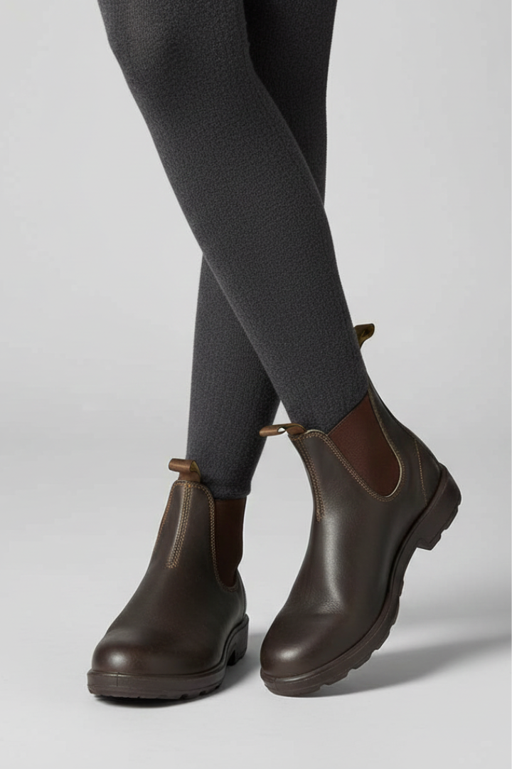 Brown leather boots worn with gray tights on a light gray background