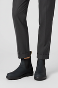 Black rain boots worn with dark gray pants on a white background