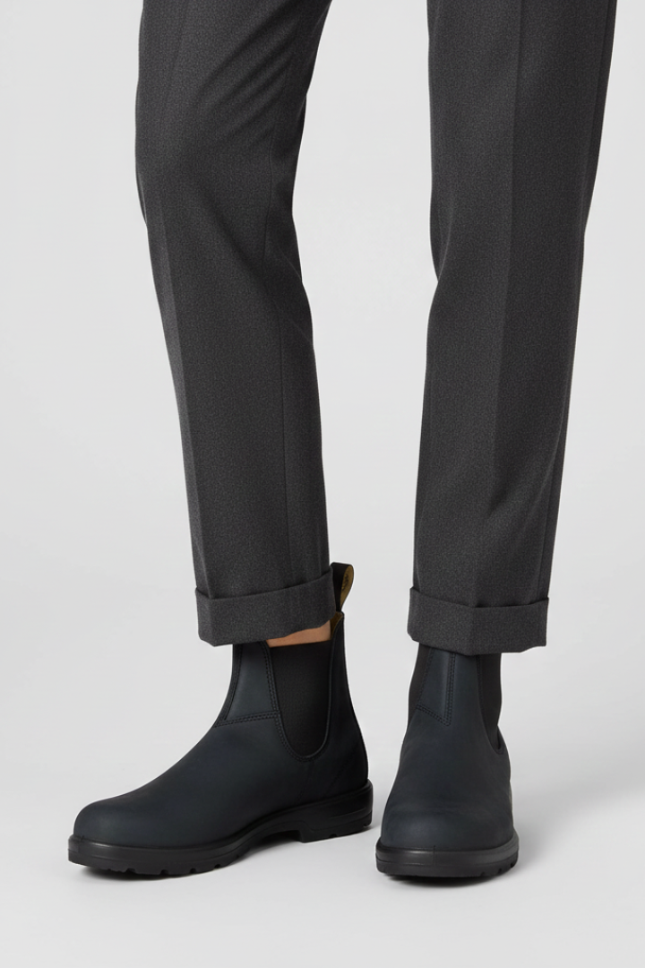 Black rain boots worn with dark gray pants on a white background