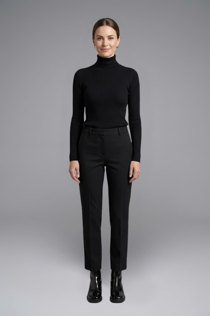 Person wearing a black turtleneck and black pants on a gray background