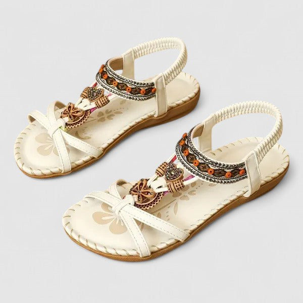 Pair of white sandals with decorative straps on a light gray background