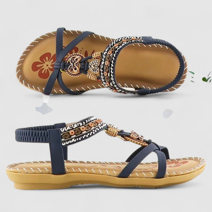 Pair of embellished sandals with decorative straps on a light gray background