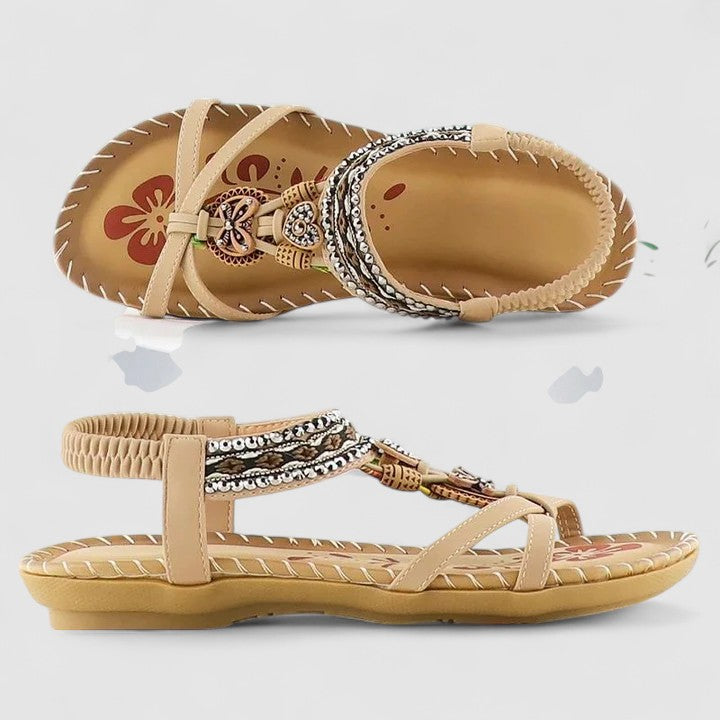 Beige sandals with decorative straps on a light gray background