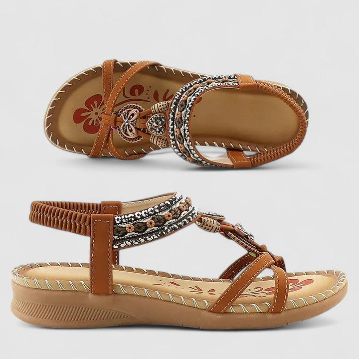 Pair of brown sandals with decorative straps on a light gray background