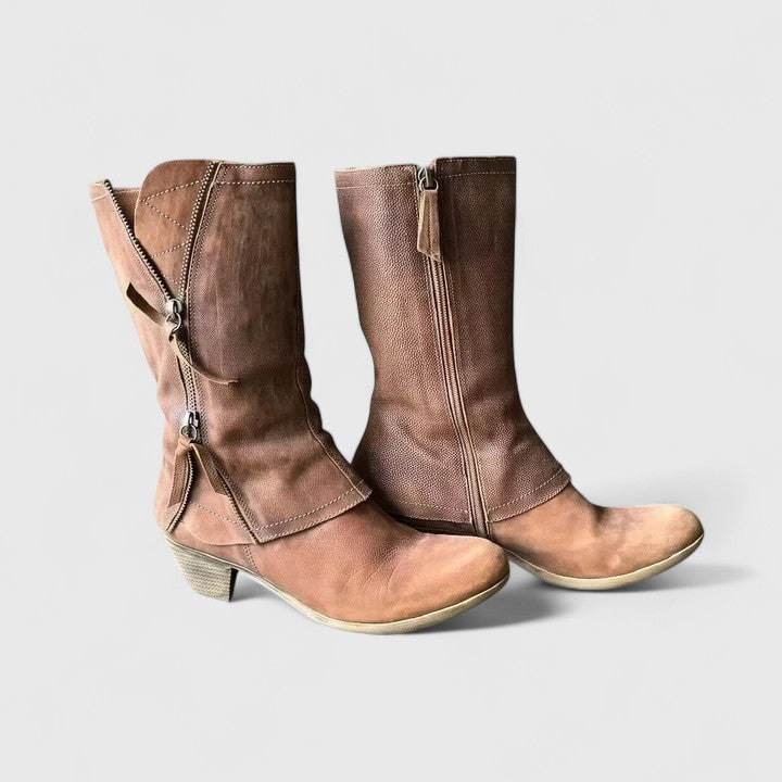Pair of brown leather boots with zippers on a light gray background