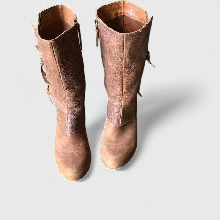 Pair of brown leather knee-high boots on a light gray background
