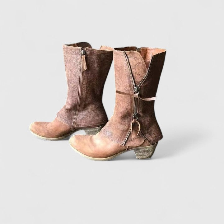 Pair of brown leather boots with zippers on a light gray background