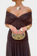 Woman holding a decorative clutch purse against a plain background