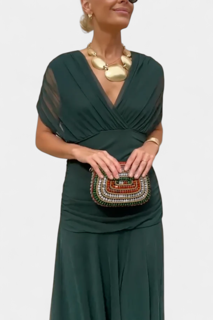 Woman wearing a green dress holding a beaded handbag on a white background