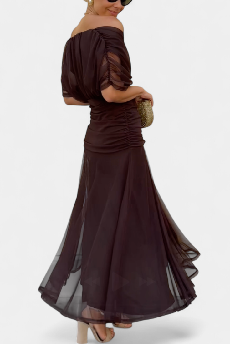 Woman wearing a dark brown off-shoulder dress with sheer sleeves on a white background