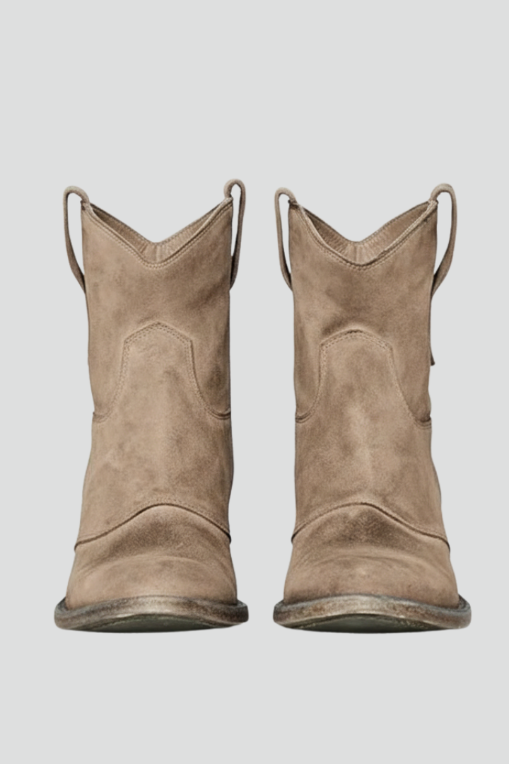 Pair of brown suede cowboy boots on a light gray background
