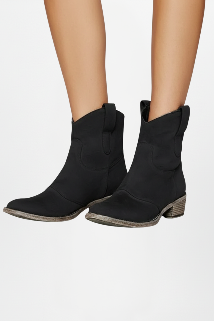 Black ankle boots worn by a person on a white background
