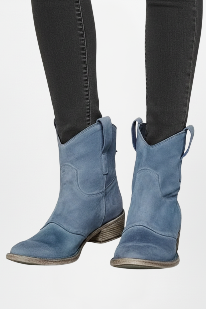 Blue cowboy boots worn with black jeans on a white background