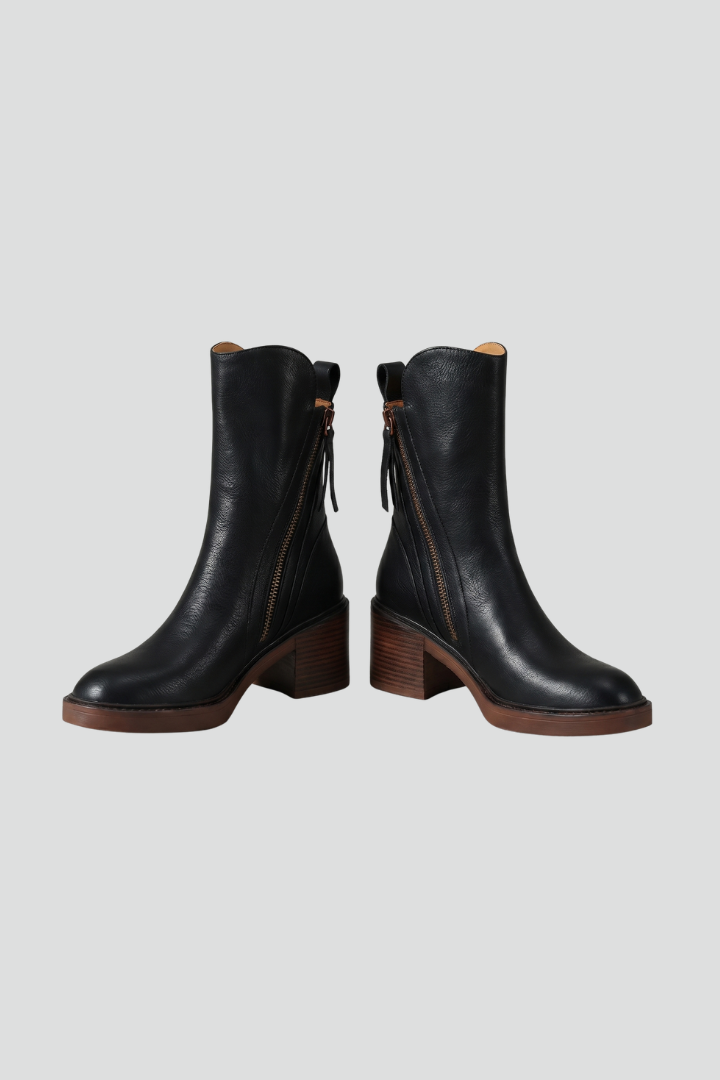 Pair of black leather boots on a light gray background