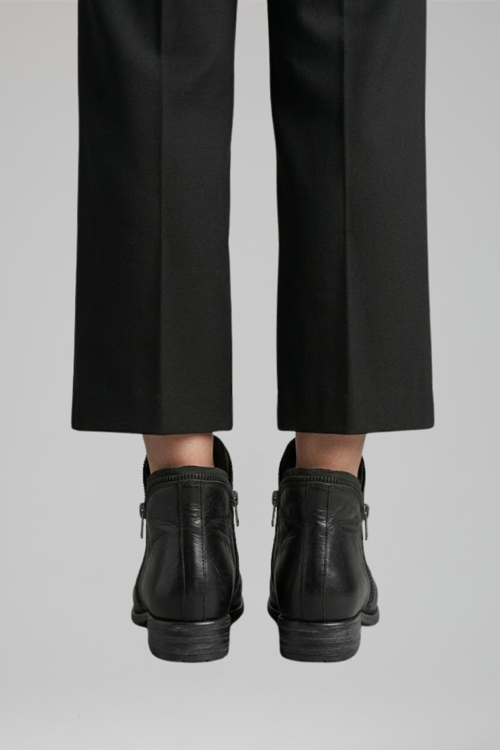 Black leather boots worn with black pants on a light gray background