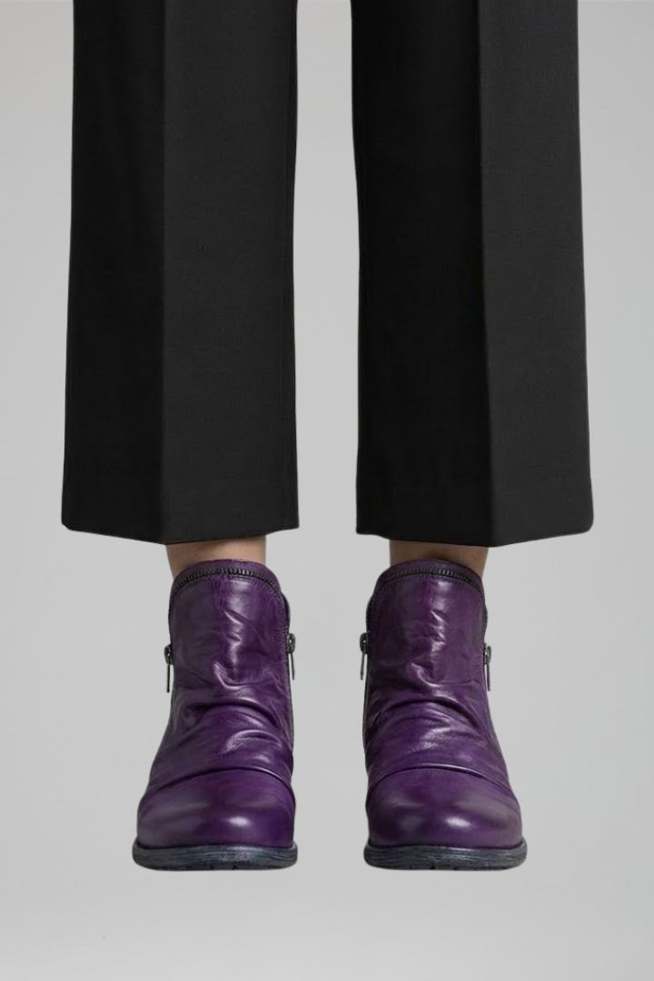 Purple boots worn with black pants on a plain background