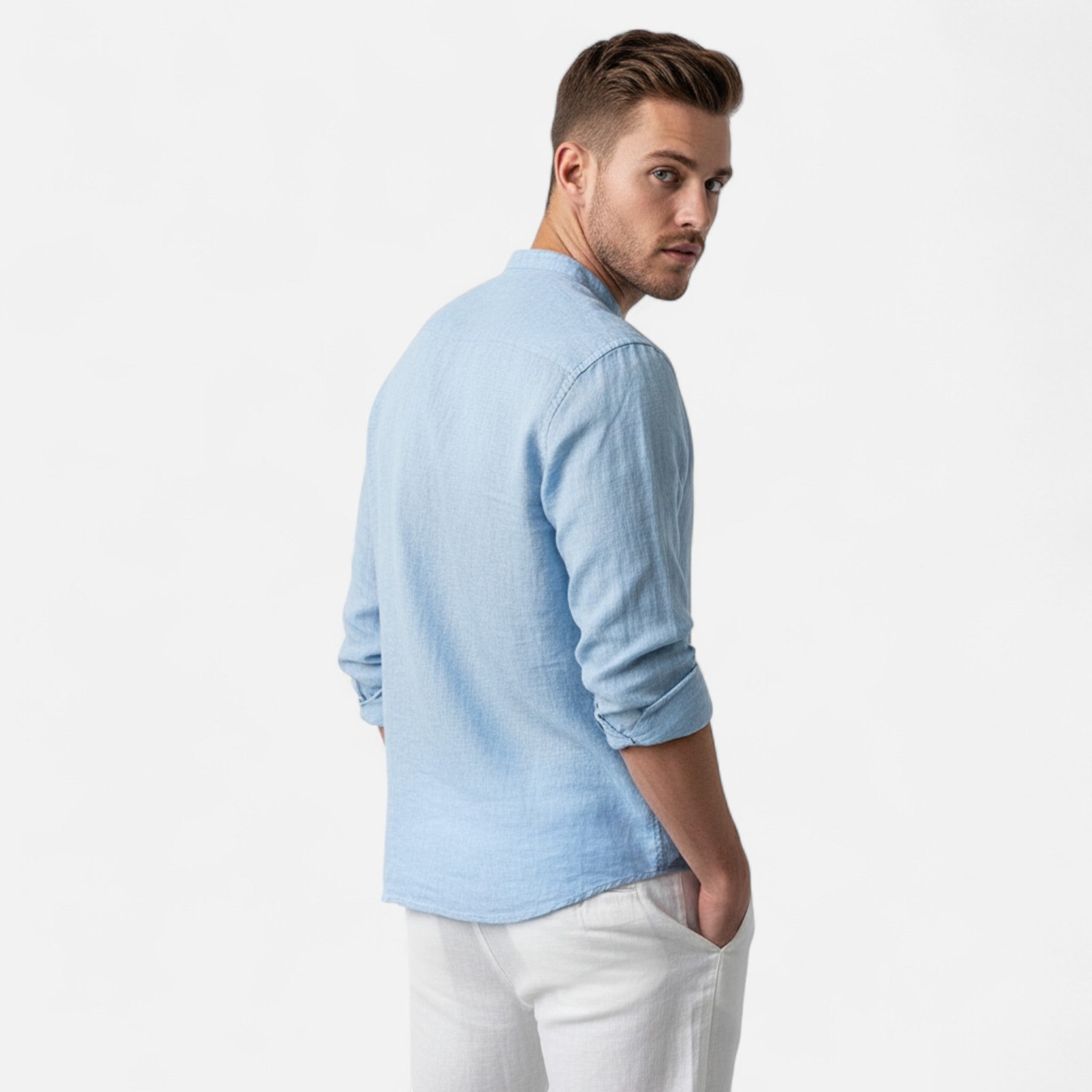 Man wearing a light blue shirt and white pants on a plain background