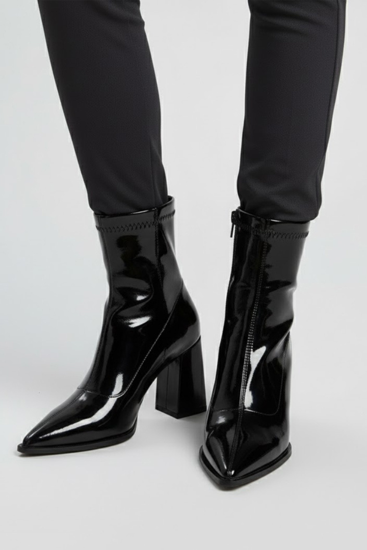 Black patent leather boots worn with black pants on a white background