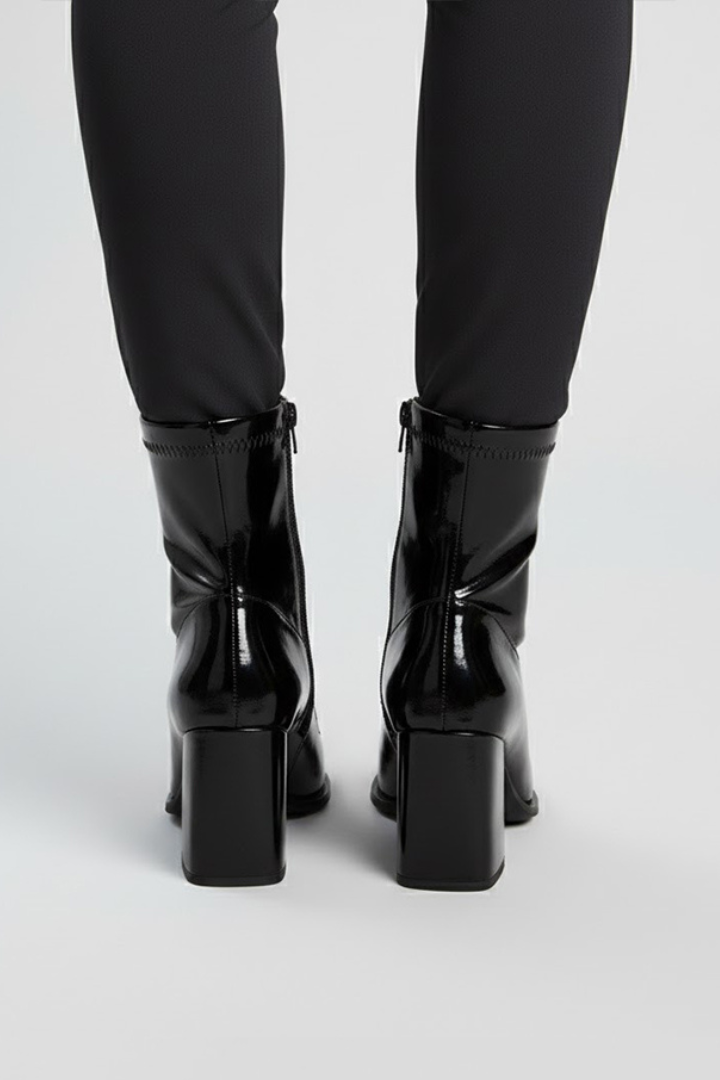Black high-heeled boots worn with black leggings on a white background