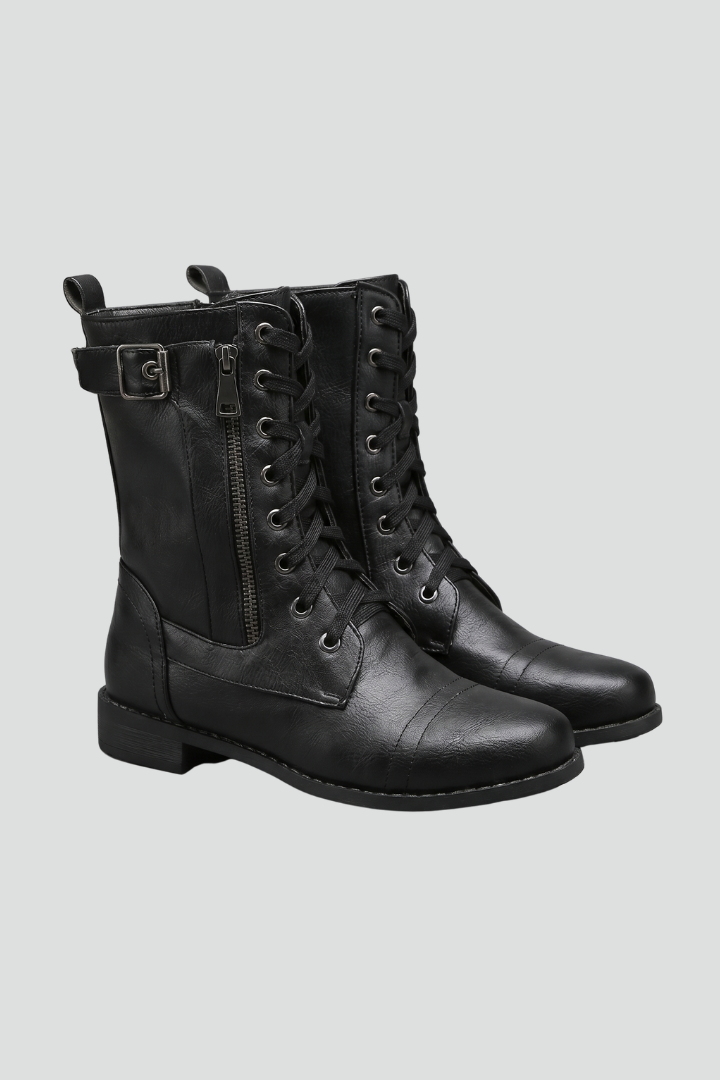 Pair of black leather boots with laces on a light gray background