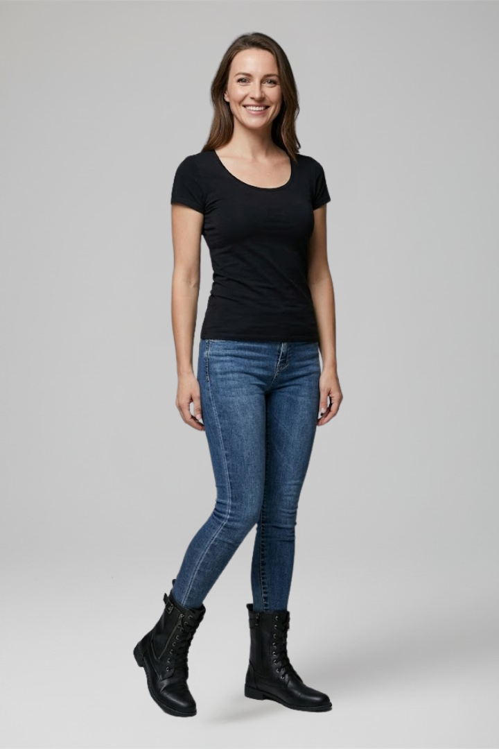 Woman wearing a black t-shirt, blue jeans, and black boots on a gray background