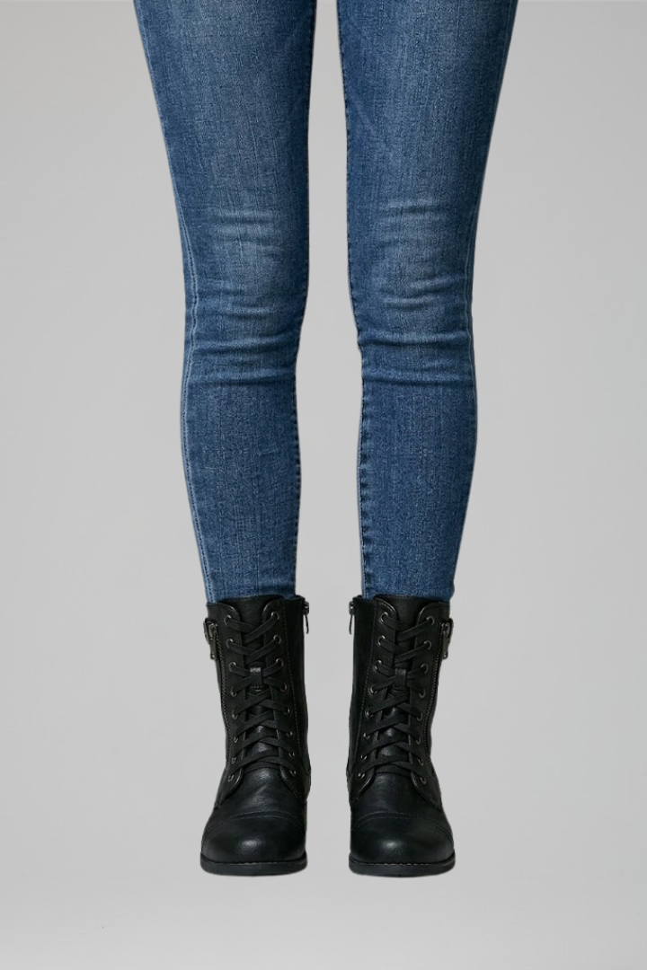 Person wearing blue jeans and black boots on a gray background