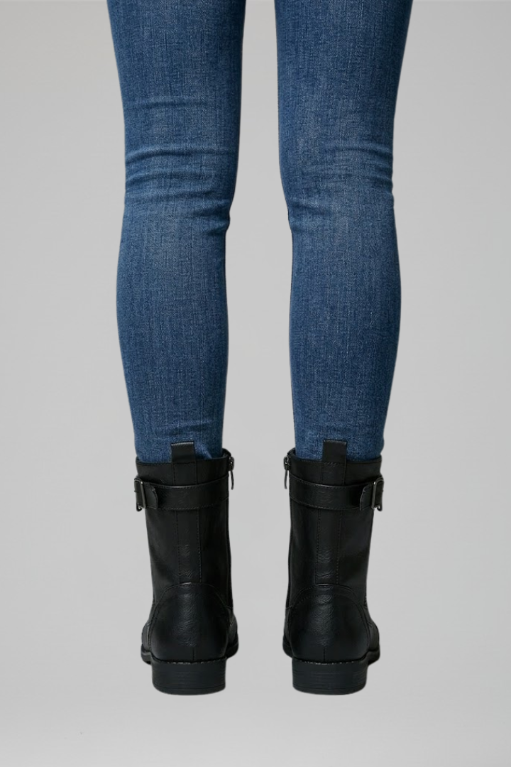 Blue jeans and black boots on a gray background
